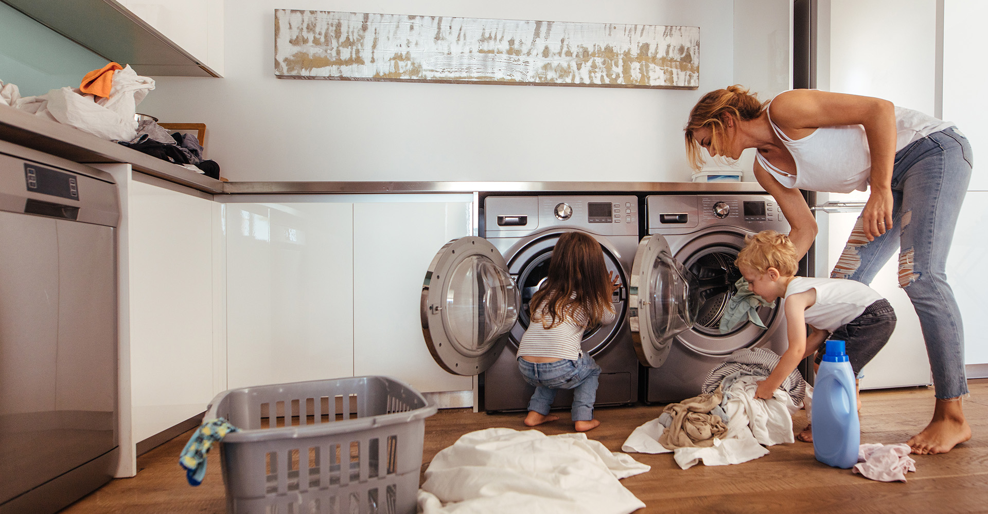 A woman doing laundry with her son and daughter at home